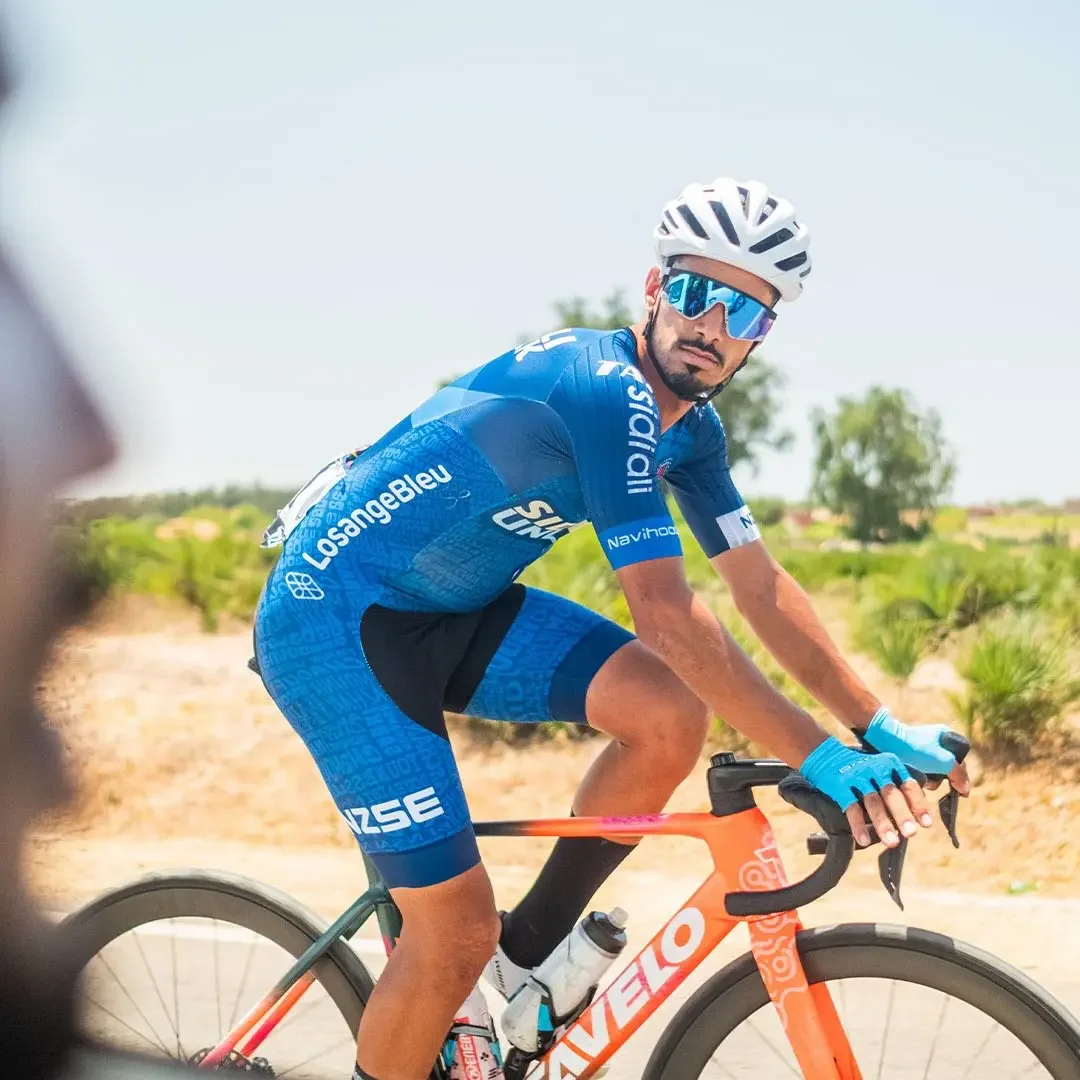 Sidi Ali cyclist looking toward the camera while riding an orange bicycle